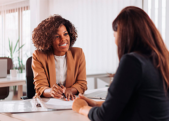 two women talking over documents